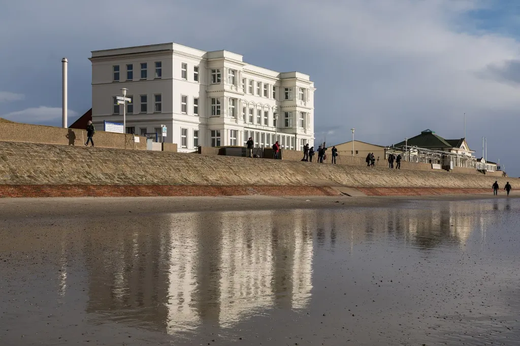 Haus am Weststrand und Giftbude auf Norderney, gespiegelt im nassen Sand