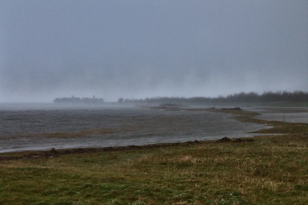 Aufgewühlte Nordsee im Regen am Außenhafen von Hooksiel während einer Wintersturmflut