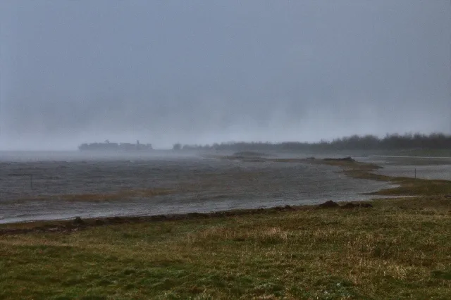 Aufgewühlte Nordsee im Regen am Außenhafen von Hooksiel während einer Wintersturmflut
